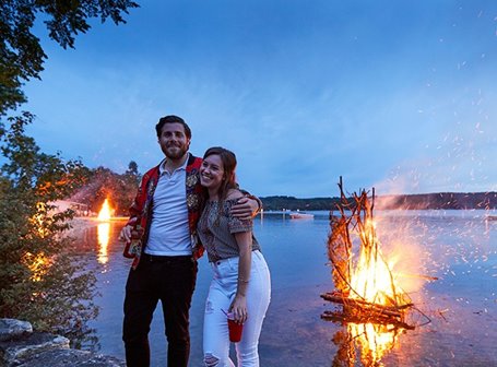 Couple in front of a bonfire at the lake.