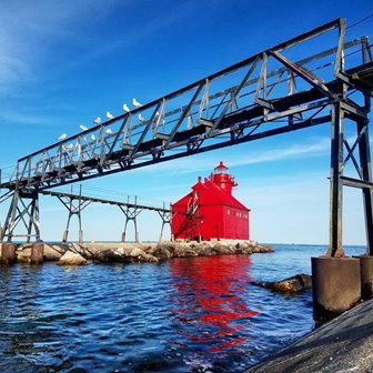 A red lighthouse on a rocky point.