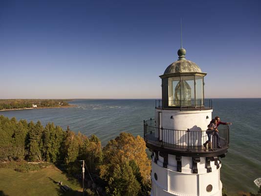 Person on a lighthouse balcony looking out over the lake.