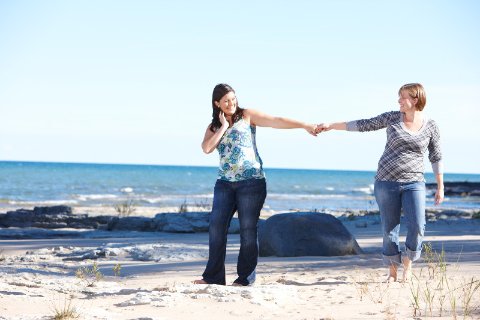 Couple holding hands on the beach and smiling at each other